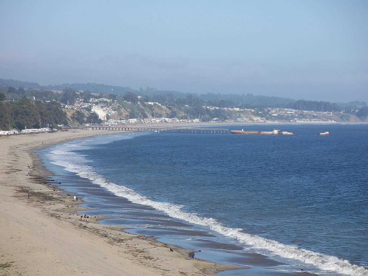 Seacliff State Beach in Aptos, California, with sandy cove, blue Pacific Ocean, fishing pier and the SS Palo Alto cement ship in the distance